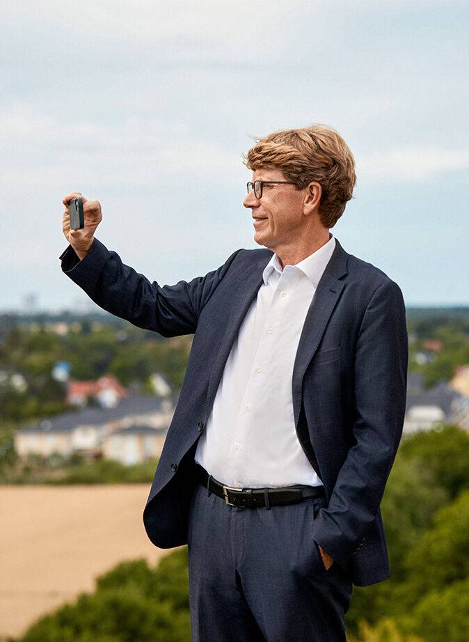 Prof. Dr.-Ing. Engelbert Lütke Daldrup, Aufsichtsratsmitglied der berlinovo, fotografiert mit dem Handy in die Ferne.
