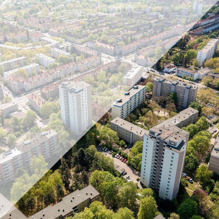 Berlin von schräg oben mit mehreren Hochhäusern, weiteren Häusern, Straßen, Autos und grünen Bäumen Berlin von schräg oben mit mehreren Hochhäusern, weiteren Häusern, Straßen, Autos und grünen Bäumen